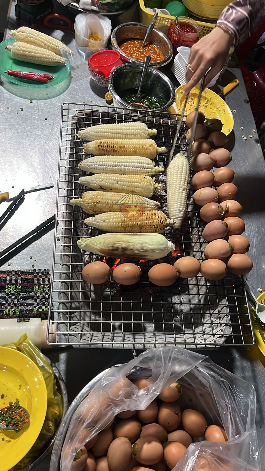 Puesto callejero de la Street food Cocinando maíz, huevos... a la barbacoa